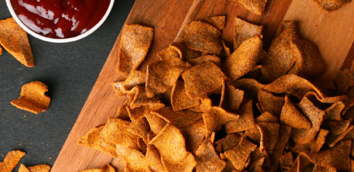 Assortment of healthy baked chips in bowls on office desk with laptop